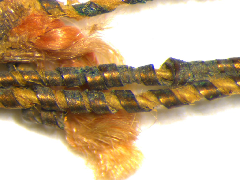 Close-up view of a thread used for the endband in an Ottoman manuscript. The copper thread which is today corroded, was twisted around a core made of silk yarn. This type of metallic thread was commonly used during the Ottoman era in book production.